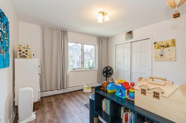 playroom with baseboard heating and wood finished floors