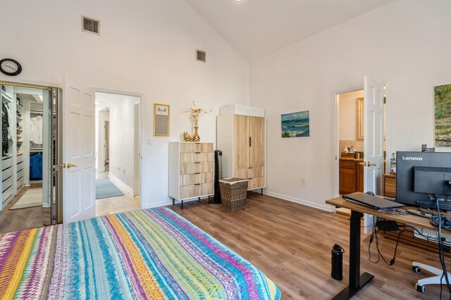 bedroom with high vaulted ceiling, baseboards, wood finished floors, and visible vents
