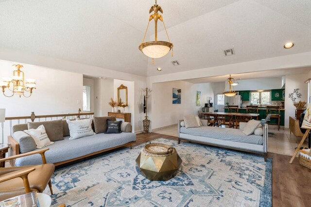 living area featuring a healthy amount of sunlight, visible vents, light wood-style flooring, and lofted ceiling