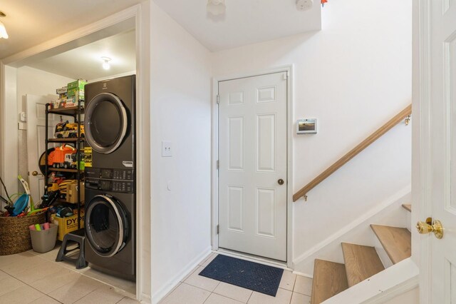 laundry room with baseboards, stacked washer / drying machine, light tile patterned floors, and laundry area