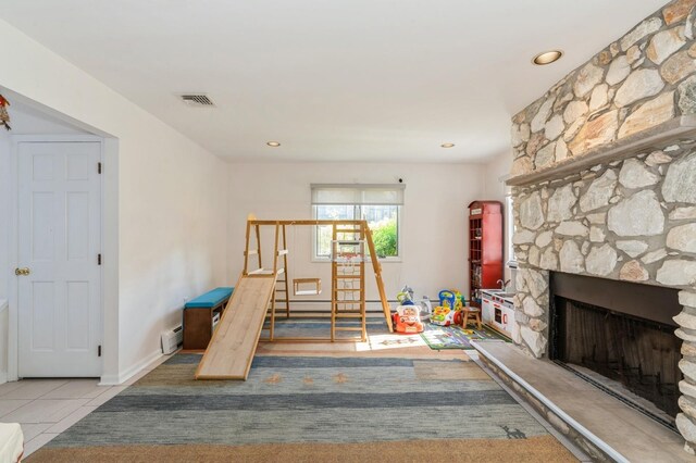 tiled living area with visible vents, a fireplace, stairs, a baseboard heating unit, and recessed lighting