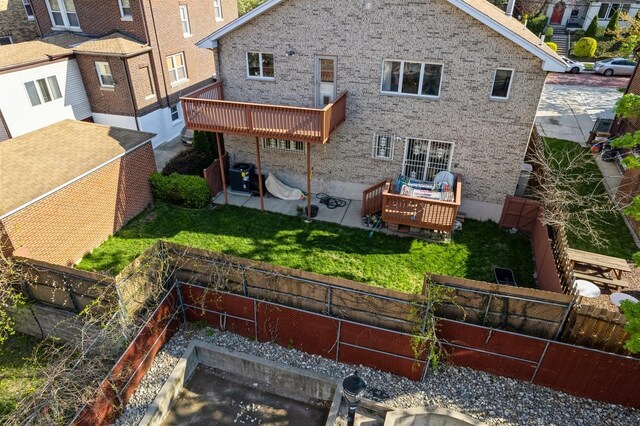 back of property featuring brick siding, a fenced backyard, a deck, and cooling unit