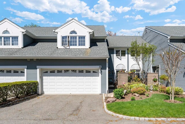 view of front of house featuring an attached garage, roof with shingles, and driveway