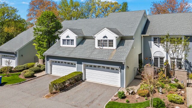 view of front of house featuring a garage, a shingled roof, and aphalt driveway