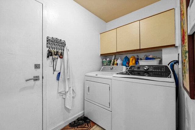 washroom with baseboards, cabinet space, and washer and clothes dryer