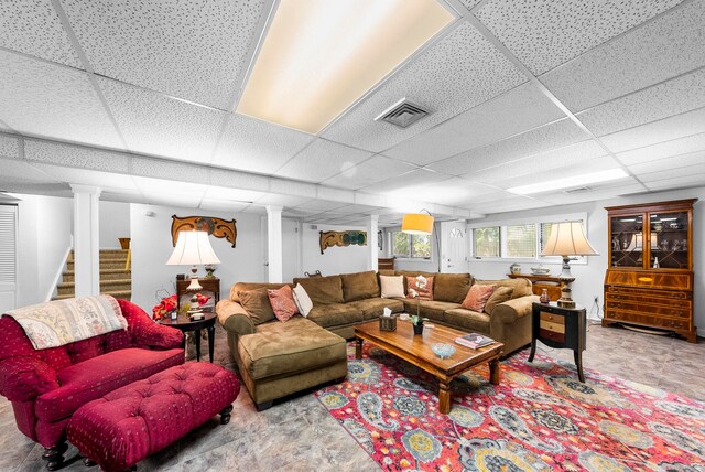 living area featuring visible vents, a drop ceiling, and stairway