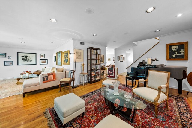 living room with light wood-type flooring, ornamental molding, recessed lighting, and stairway
