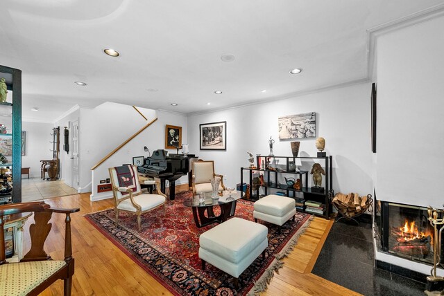 living area featuring a fireplace with flush hearth, ornamental molding, recessed lighting, and wood finished floors