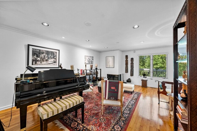 living area with light wood-style floors, baseboards, ornamental molding, and recessed lighting