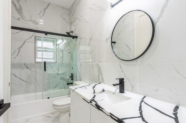97 Irving St Unit 1, Jersey City, NJ 07307 - bathroom featuring tile walls, marble tiled flooring, toilet, bath / shower combo with glass door, and vanity