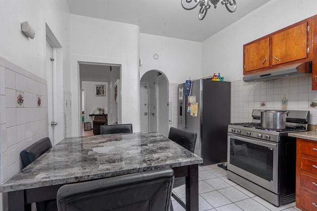 6910 Jackson St, Guttenberg, NJ 07093 - kitchen with stainless steel appliances, under cabinet range hood, light tile patterned floors, a kitchen breakfast bar, and brown cabinets