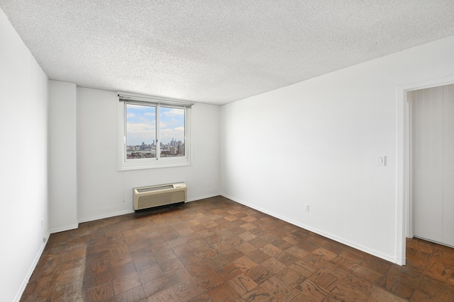 empty room featuring baseboards, a textured ceiling, and an AC wall unit