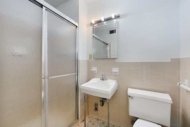 bathroom featuring toilet, a wainscoted wall, tile walls, visible vents, and a shower stall