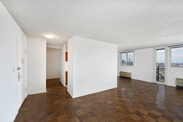 empty room with baseboards, radiator, and a textured ceiling