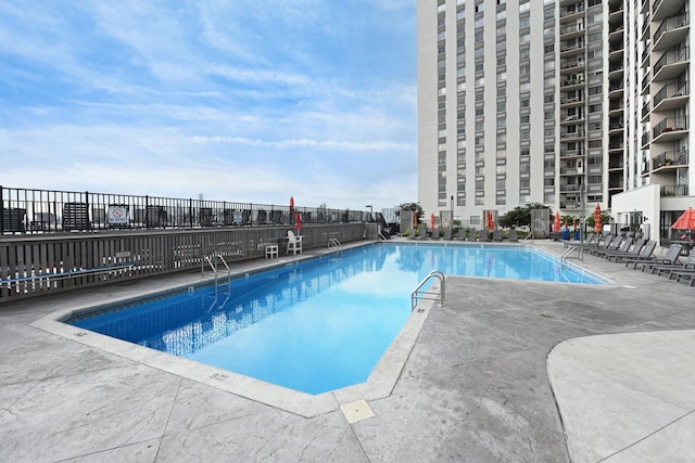 community pool with a patio and fence