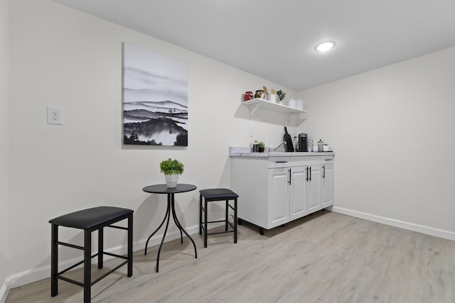 bar with light wood-type flooring, bar area, and baseboards