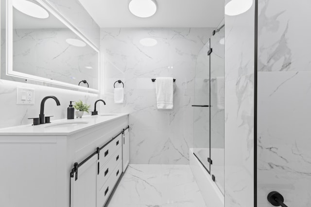 bathroom featuring double vanity, a marble finish shower, marble finish floor, stone wall, and a sink