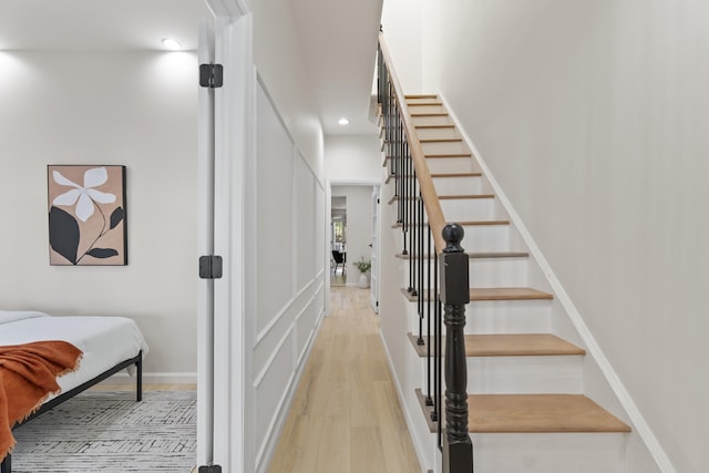 staircase with recessed lighting, a towering ceiling, baseboards, and wood finished floors