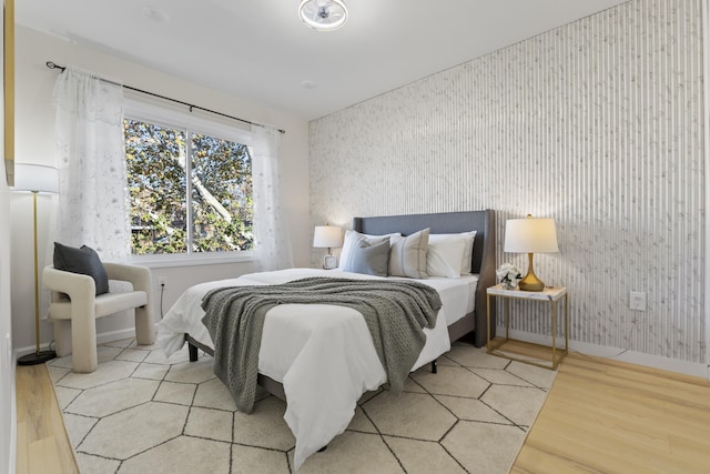 bedroom with wallpapered walls, light wood-style flooring, and baseboards