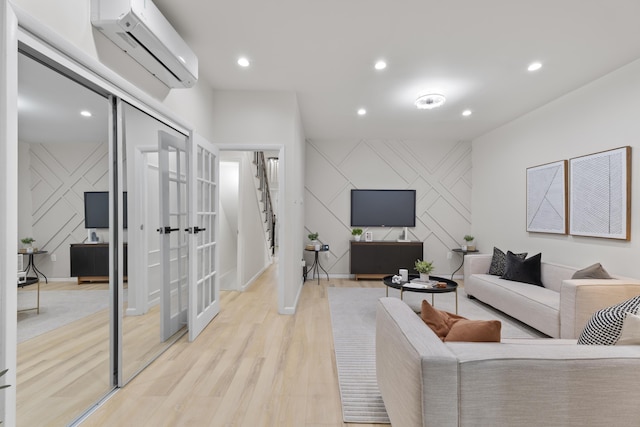 living room with baseboards, a wall unit AC, an accent wall, light wood-type flooring, and recessed lighting