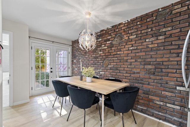 dining space featuring light wood-type flooring, french doors, baseboards, and brick wall