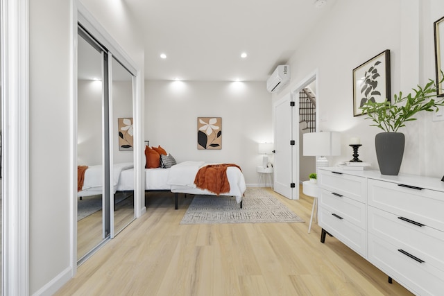 bedroom with baseboards, recessed lighting, a wall unit AC, and light wood-style floors