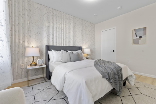 bedroom with light wood-type flooring, baseboards, and wallpapered walls