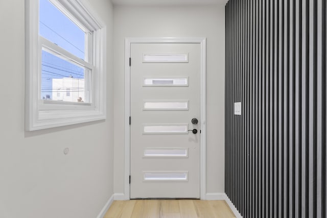 doorway featuring light wood-style flooring and baseboards