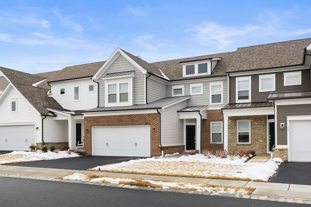 townhome / multi-family property featuring metal roof, brick siding, aphalt driveway, and a standing seam roof