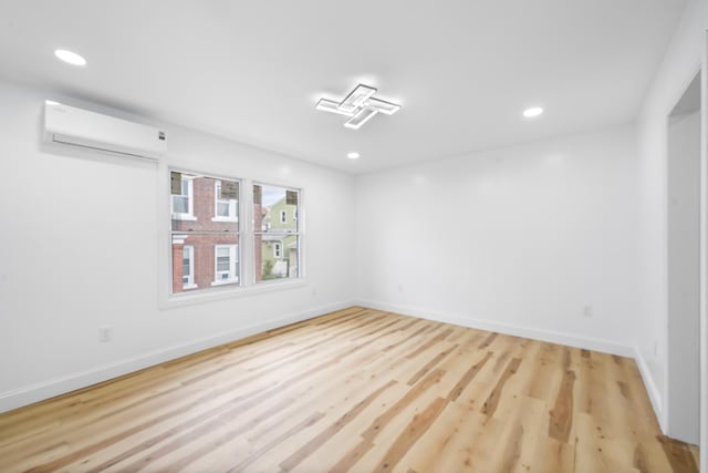 1 Sisson Ct, Bayonne, NJ 07002 - empty room featuring a wall mounted air conditioner, wood finished floors, baseboards, and recessed lighting