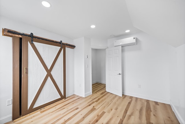 1 Sisson Ct, Bayonne, NJ 07002 - below grade area with a wall mounted AC, a barn door, recessed lighting, light wood-style flooring, and baseboards