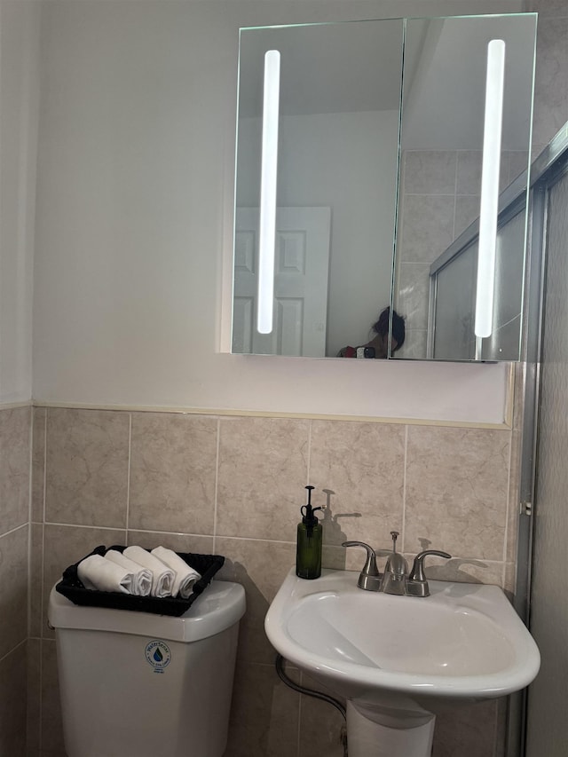 bathroom featuring tile walls, a sink, and toilet