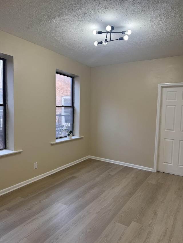 spare room with wood finished floors, a textured ceiling, and baseboards