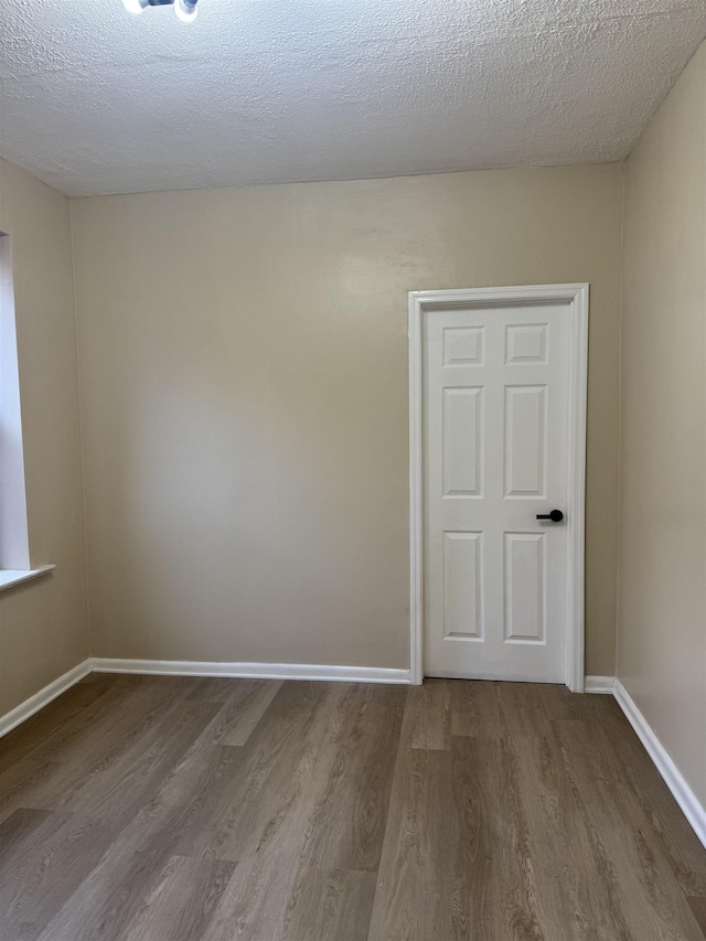 unfurnished room featuring wood finished floors, baseboards, and a textured ceiling