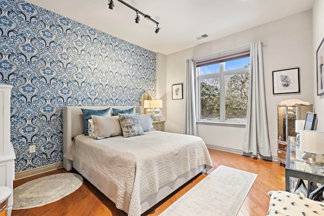 bedroom with track lighting and light hardwood / wood-style floors