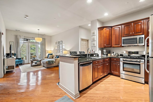 kitchen featuring sink, stainless steel appliances, decorative light fixtures, and kitchen peninsula