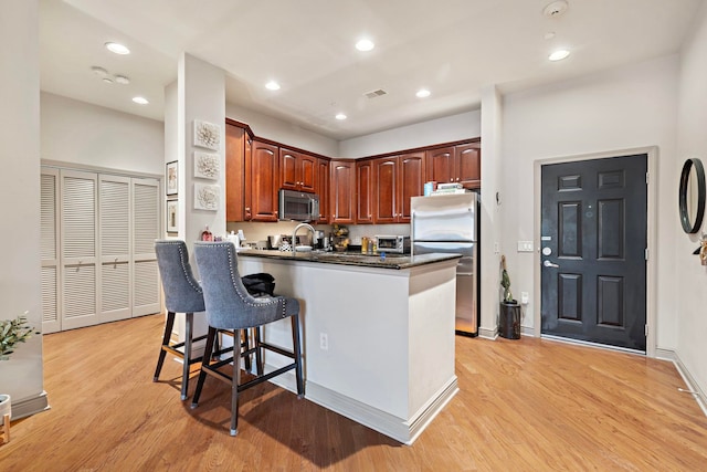 kitchen featuring stainless steel appliances, sink, light hardwood / wood-style floors, kitchen peninsula, and a breakfast bar area