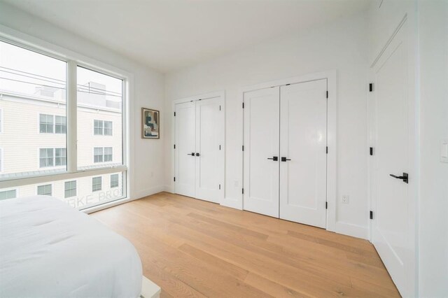 160 Brunswick St Unit 302, Jersey City, NJ 07302 - bedroom with multiple closets, light wood-style flooring, and baseboards