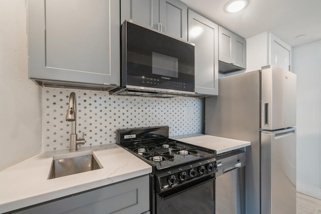 kitchen with gray cabinets, sink, appliances with stainless steel finishes, and decorative backsplash