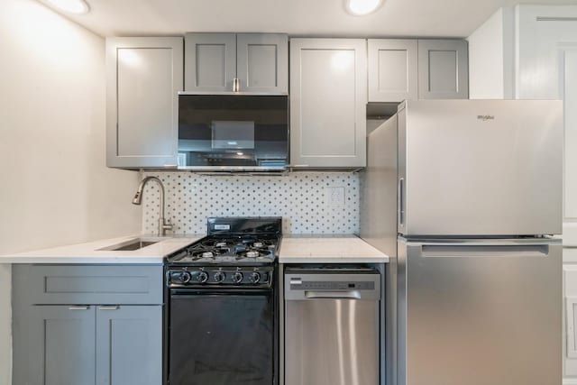 kitchen with gray cabinets, appliances with stainless steel finishes, sink, and decorative backsplash