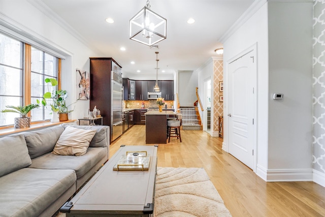 living room featuring an inviting chandelier, crown molding, and light wood-type flooring