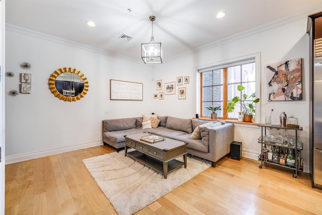 living room featuring crown molding, an inviting chandelier, and light hardwood / wood-style flooring