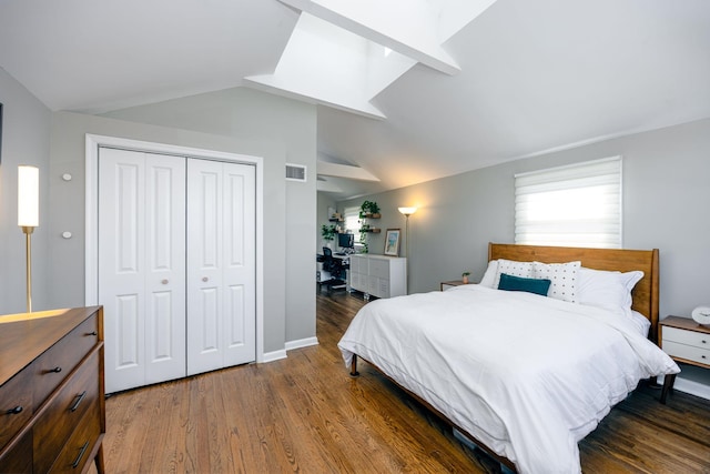 bedroom featuring visible vents, wood finished floors, a closet, vaulted ceiling with skylight, and baseboards