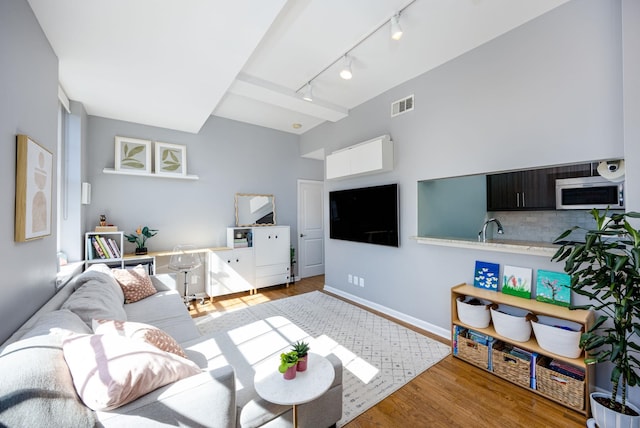 living area featuring wood finished floors, visible vents, and baseboards