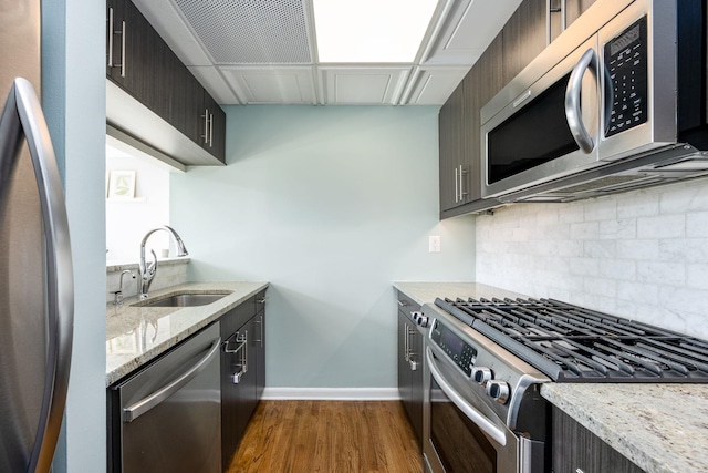 kitchen with a sink, tasteful backsplash, dark wood finished floors, stainless steel appliances, and baseboards