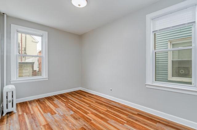 spare room featuring baseboards and light wood-style floors