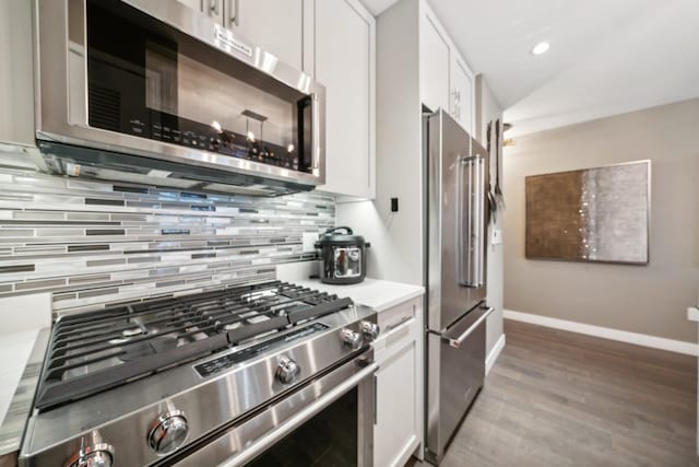 kitchen with white cabinets, decorative backsplash, hardwood / wood-style flooring, and high quality appliances