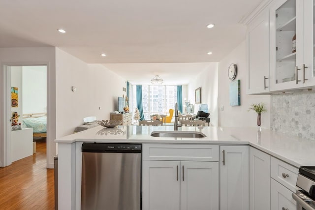 kitchen featuring sink, appliances with stainless steel finishes, white cabinets, kitchen peninsula, and light wood-type flooring