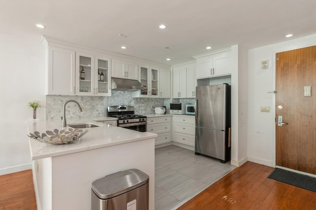 kitchen with white cabinetry, stainless steel appliances, kitchen peninsula, and sink