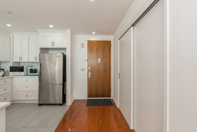 kitchen with white cabinetry, tasteful backsplash, stainless steel appliances, and light hardwood / wood-style floors